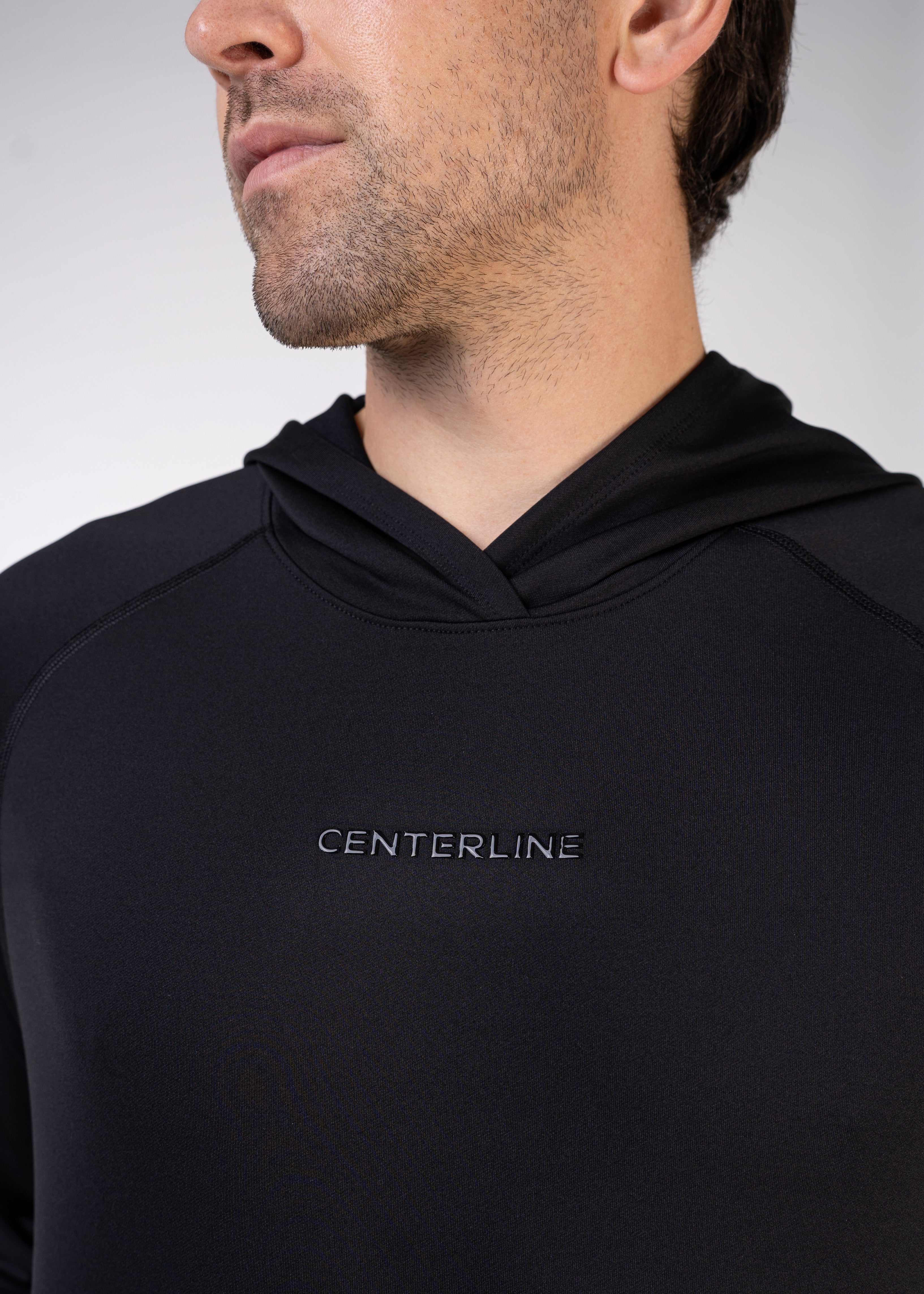 Close-up of a man's upper body wearing a black hooded sweatshirt with the word "CENTERLINE" printed on the front.