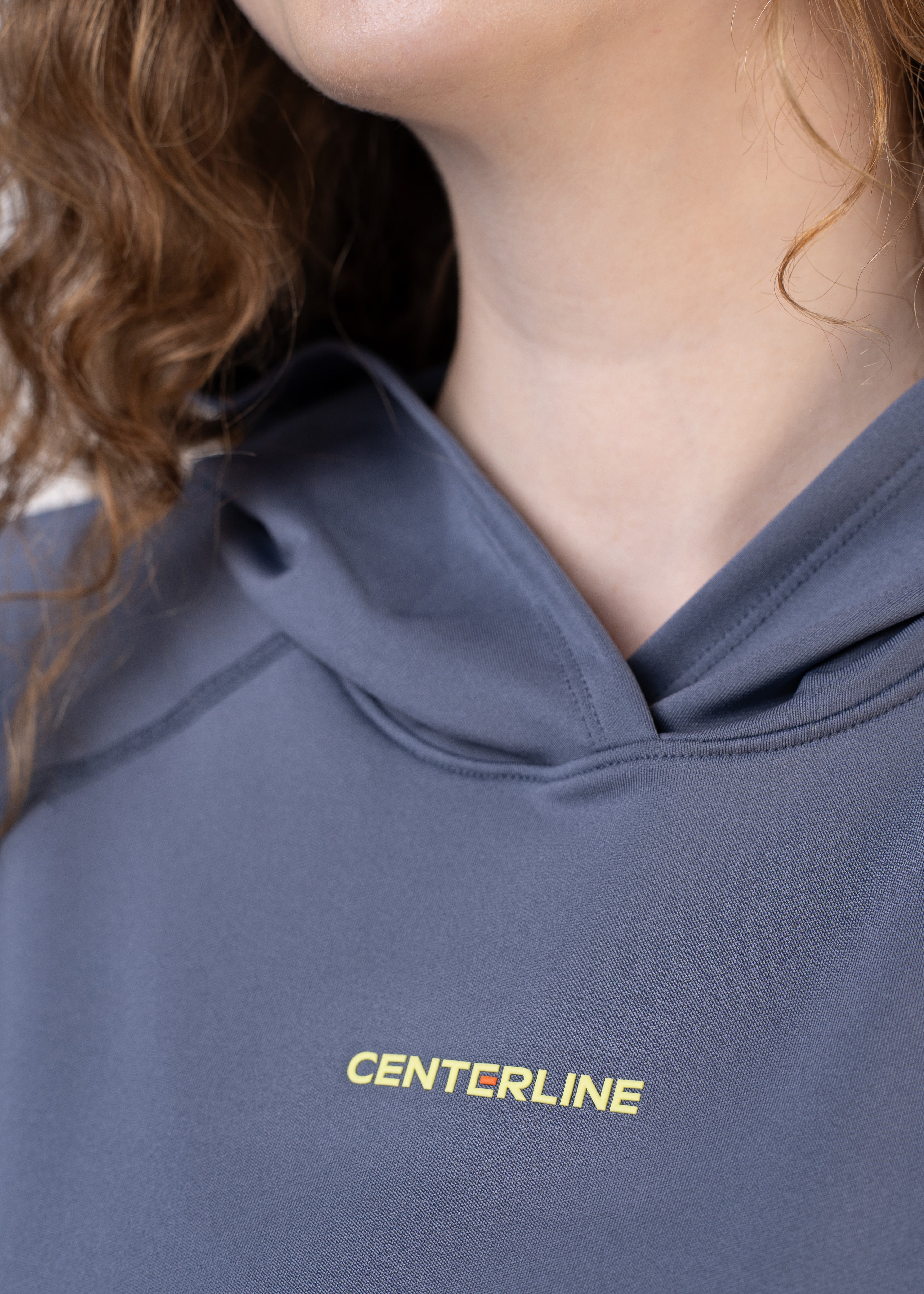 Close-up of a person wearing a heather gray hoodie with "CENTERLINE" printed in yellow.