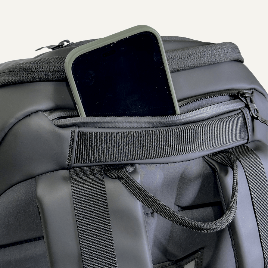 Dark gray pickleball bag by FORWRD with a smartphone in an open zippered pocket and ribbed webbing details.