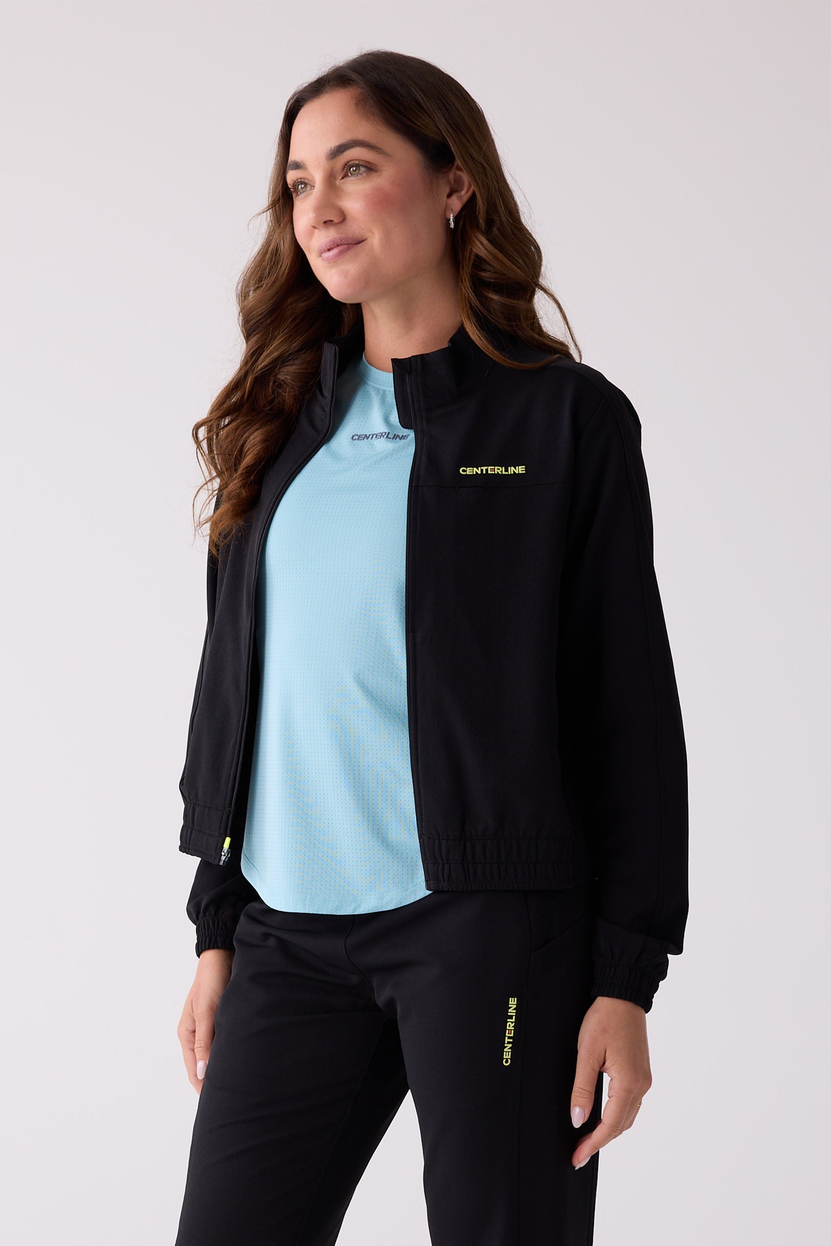 Black Women's Courtside Track Jacket by Centerline Athletics, full-zip, with yellow 'CENTERLINE' logo on chest.
