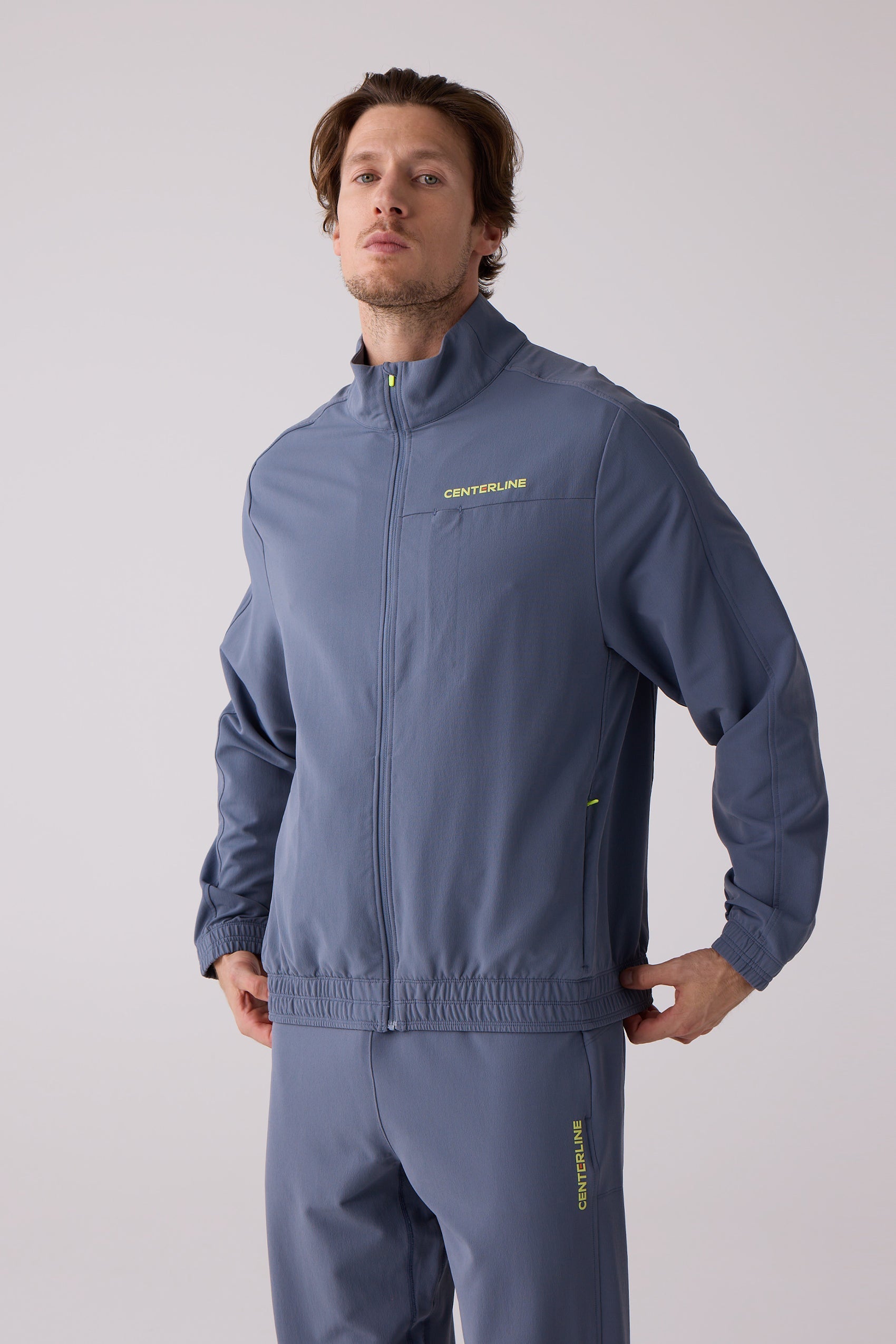 Men's blue track jacket by Centerline Athletics, featuring a stand-up collar and neon yellow accents including chest logo.