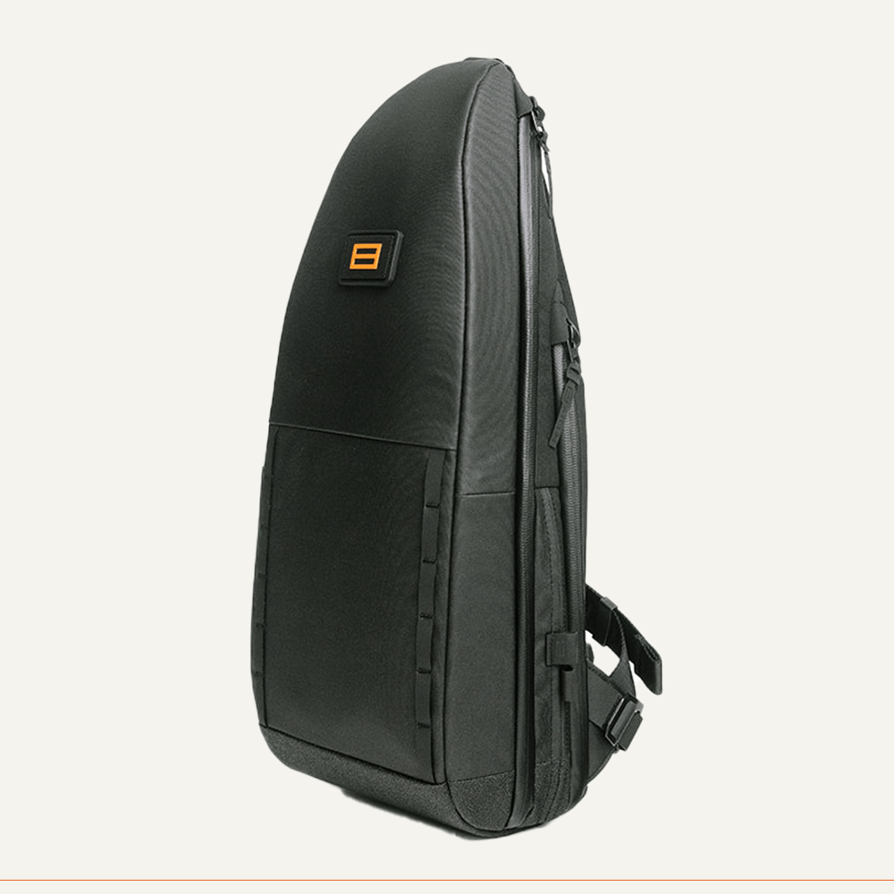 Black pickleball sling bag by FORWRD with a sleek contoured design and an orange rectangular logo, shown from the side.