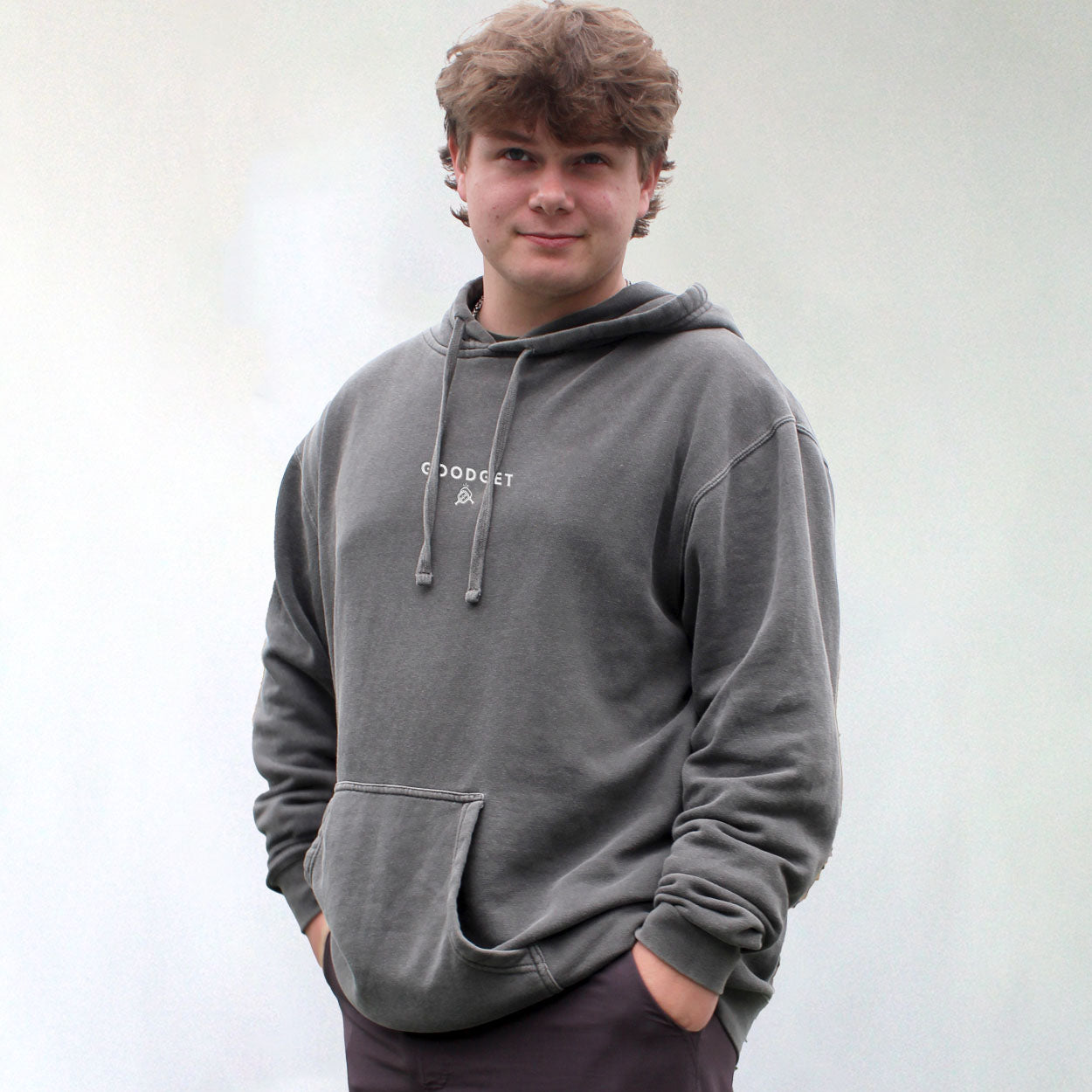 Washed charcoal grey hoodie by Good Get, with white chest logo, drawstring hood, and kangaroo pocket, on a man.