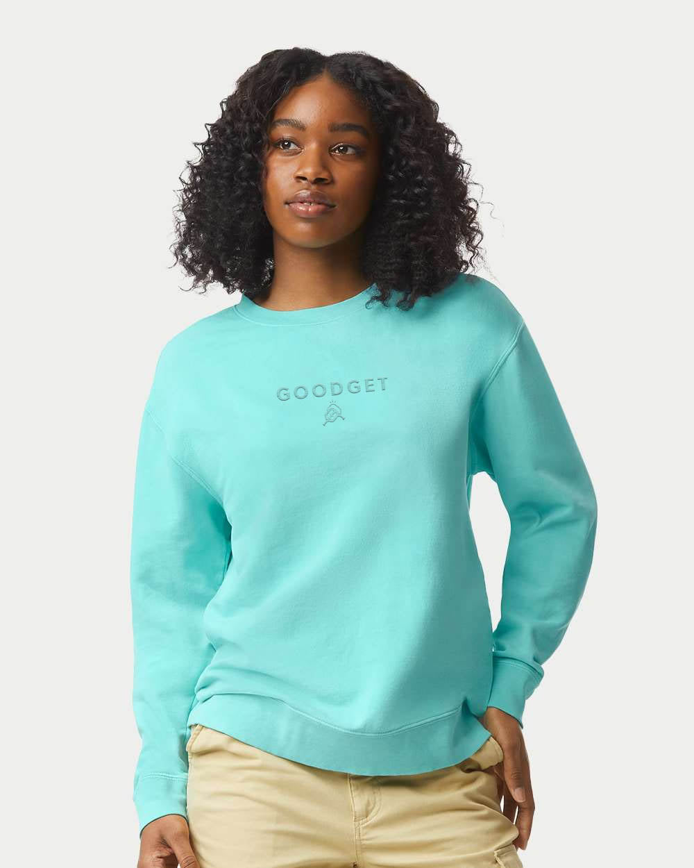 Aqua blue crewneck sweatshirt by Good Get with tone-on-tone logo on chest, worn by a woman with khaki pants.