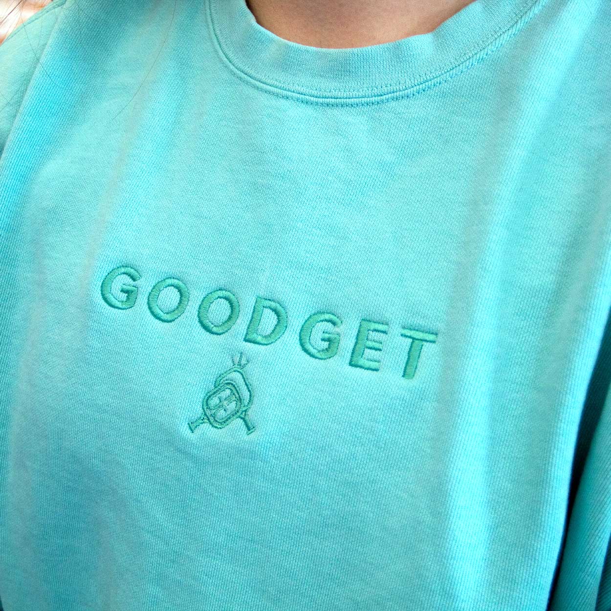 Aqua crewneck sweatshirt by Good Get with tone-on-tone embroidered brand name 'GOODGET' and a stylized emblem.