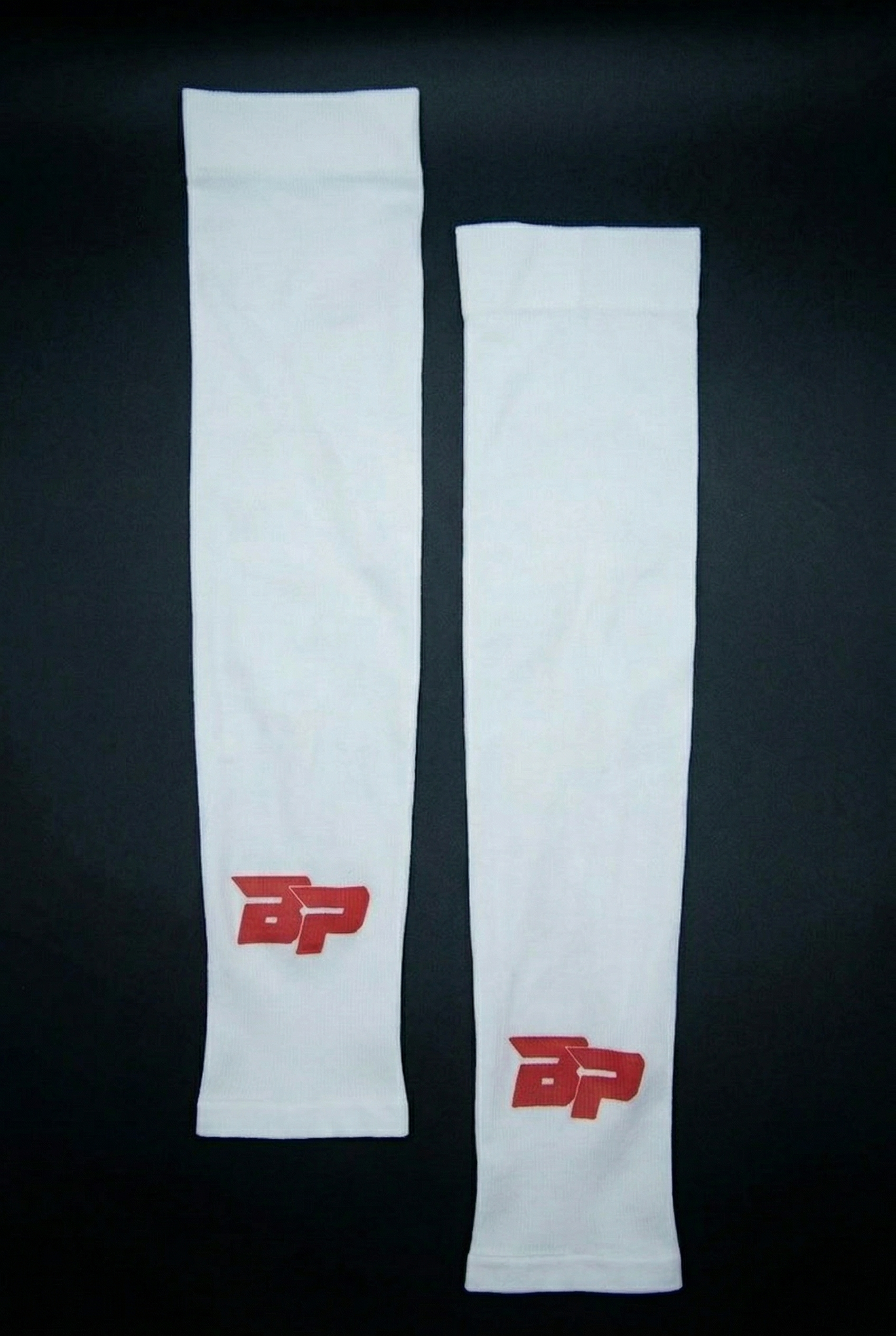 White Performance Arm Sleeves by Bodhi Pickleball, with a red BP logo on each, laid flat.