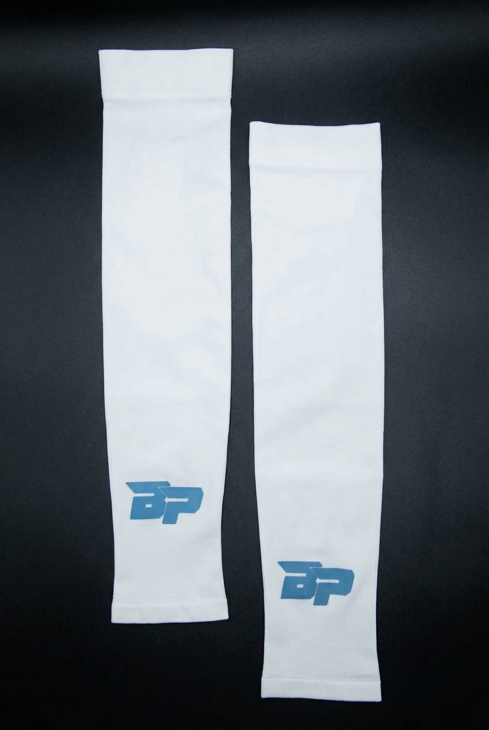 A pair of white performance arm sleeves by Bodhi Pickleball with a blue BP logo on each, against a black background.