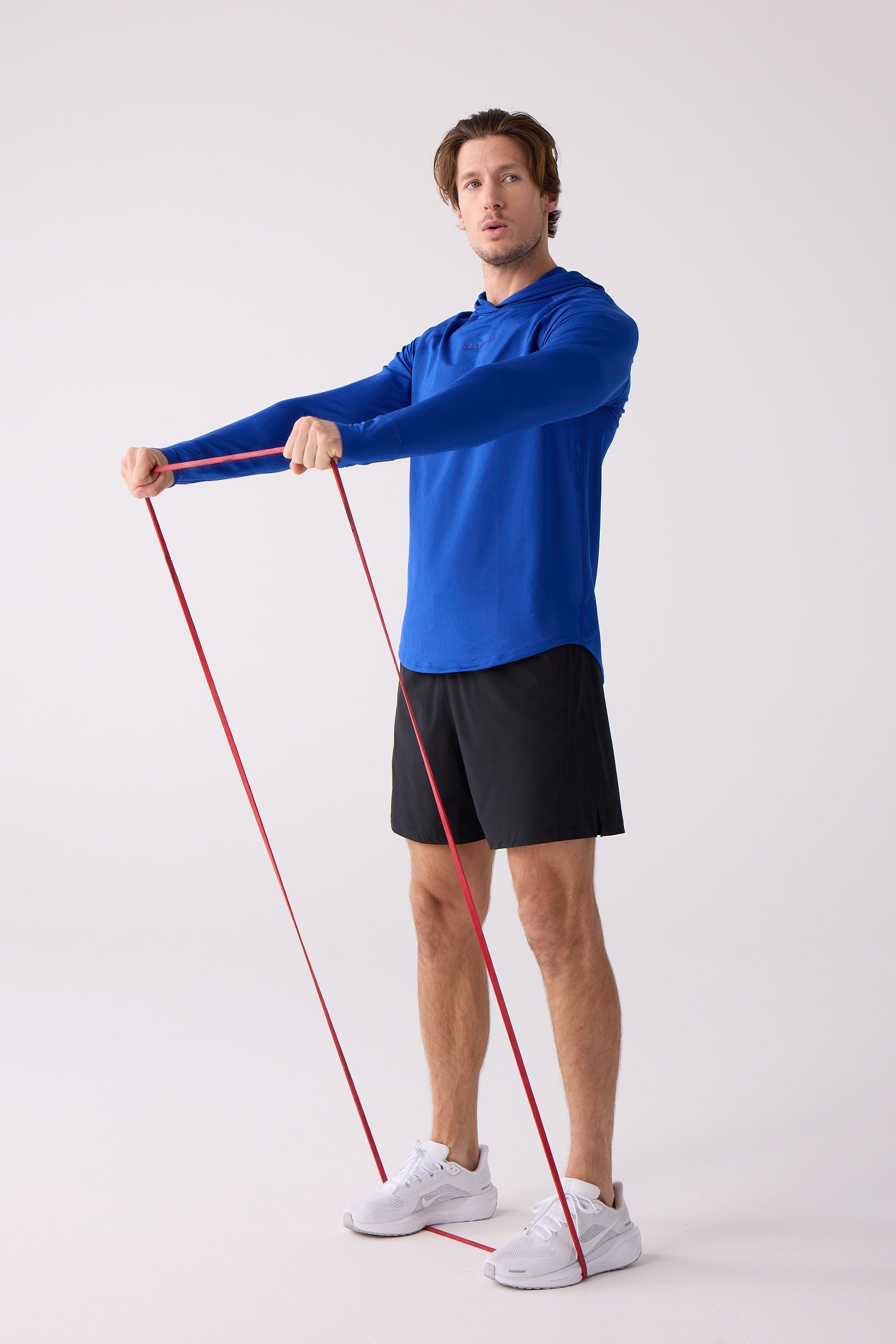 Blue men's layering hoodie by Centerline Athletics with a subtle chest logo, worn by a man exercising with a red resistance band.