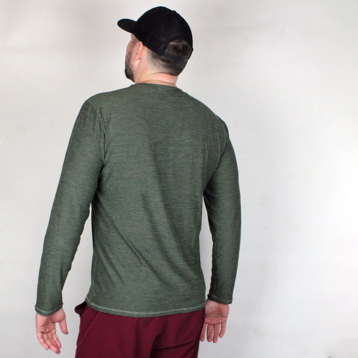 Olive green heathered performance long sleeve t-shirt by Good Get, worn by a man from the back with maroon pants and a black cap.
