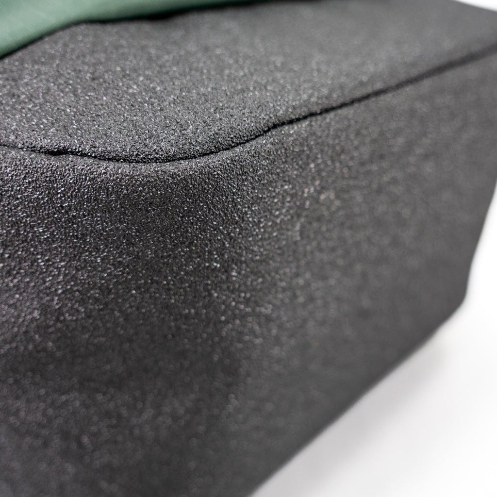 Close-up of a textured black object with a seam and a green element.
