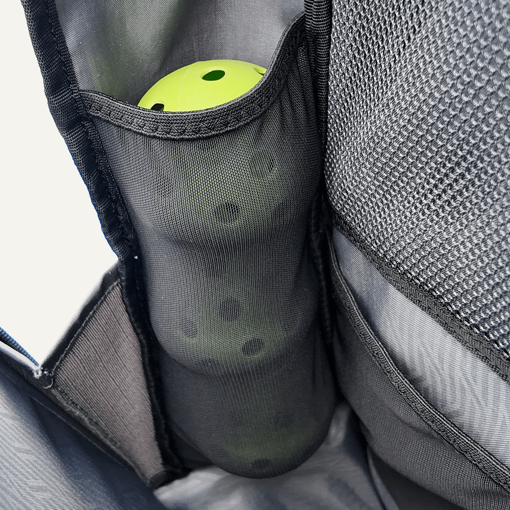 Close-up shot of a backpack with a neon green ball in a mesh pocket.