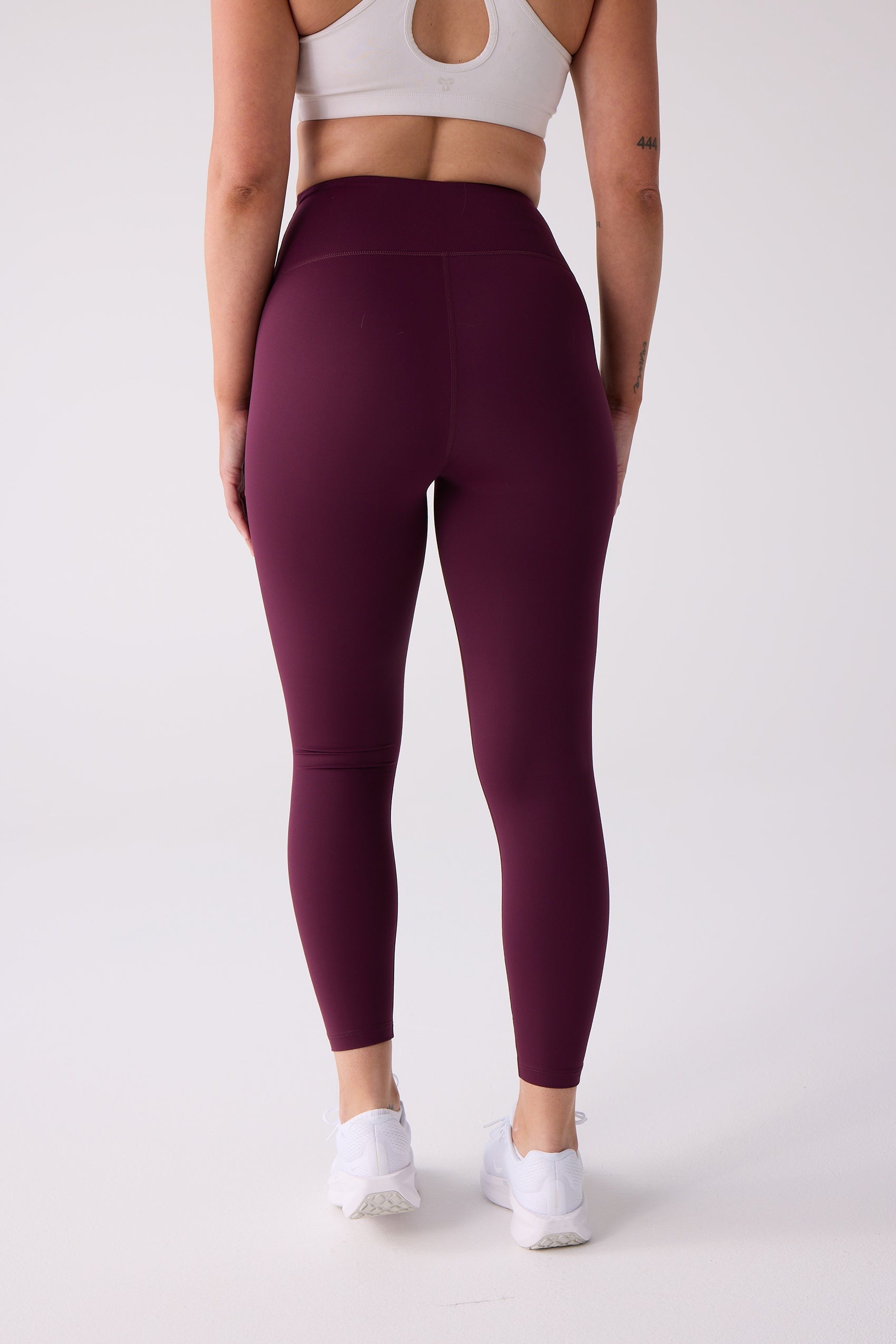 Burgundy 7/8 legging by Centerline Athletics, worn from the back with a white sports bra and white sneakers.