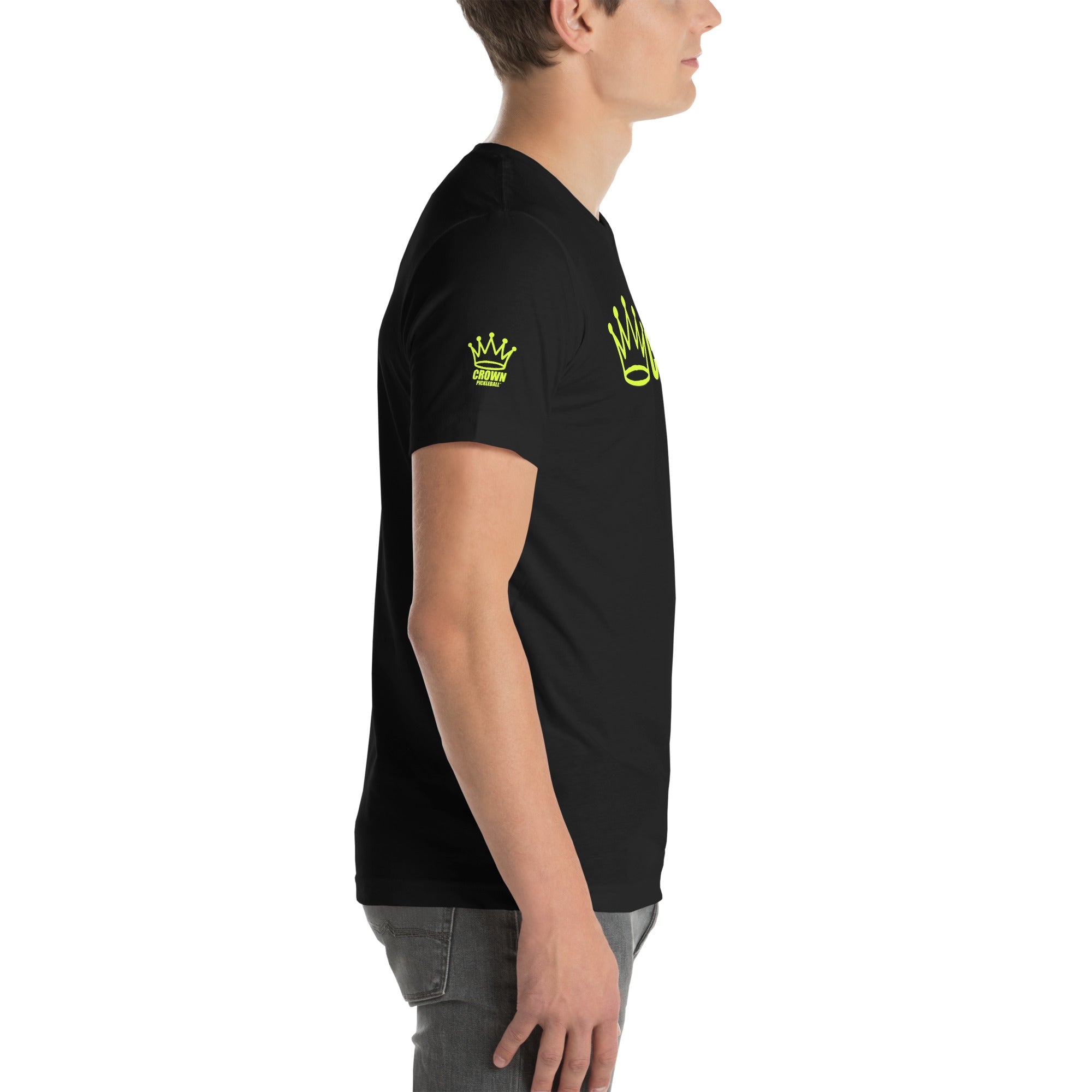 Profile shot of a man wearing a black t-shirt with yellow crown graphics and gray jeans.