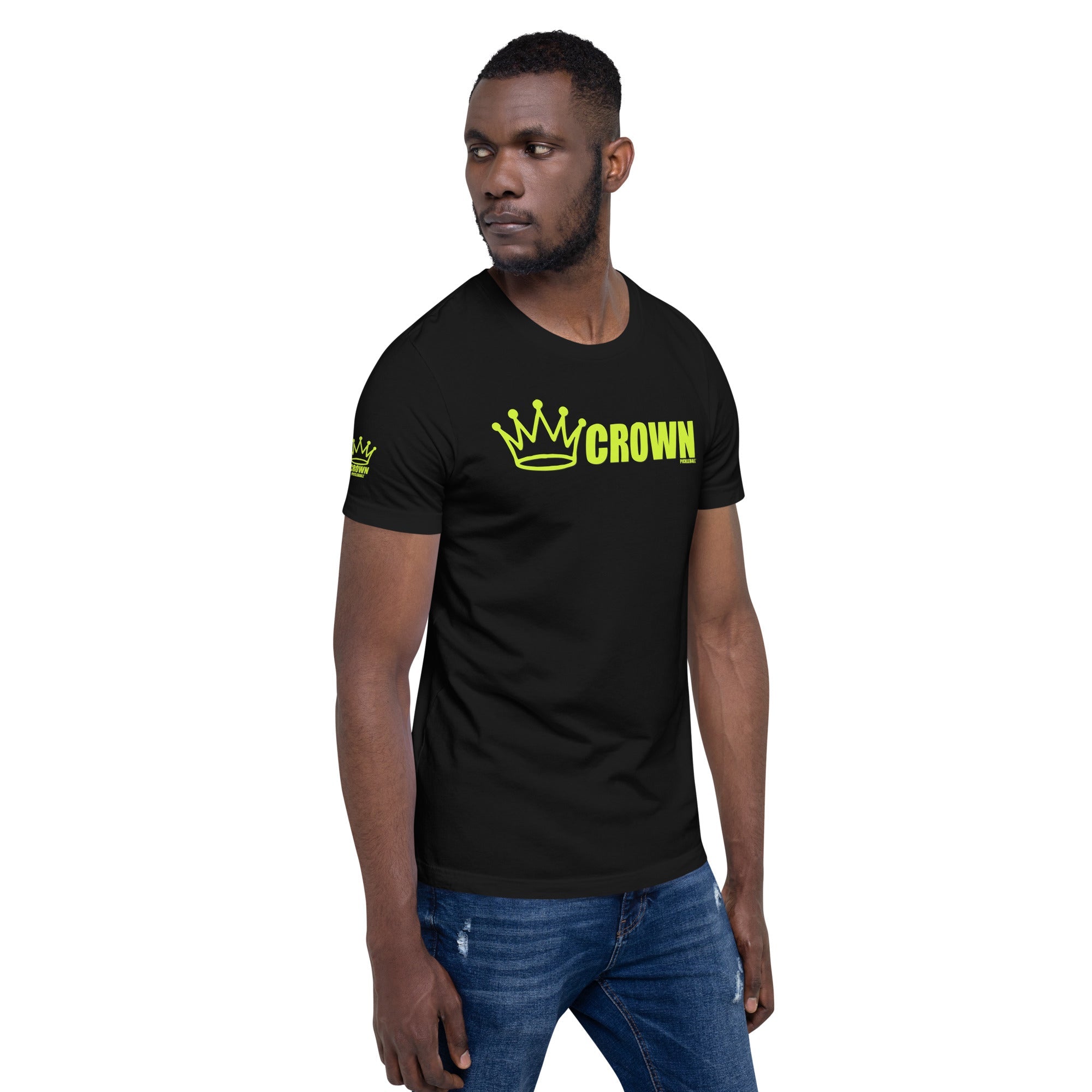 A man wearing a black t-shirt with a yellow crown logo and blue jeans.